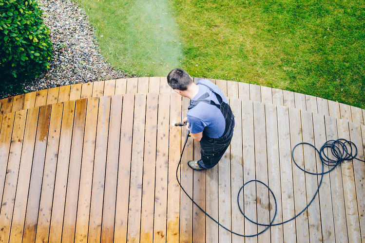 cleaning terrace with a power washer - high water pressure cleaner on wooden terrace surface